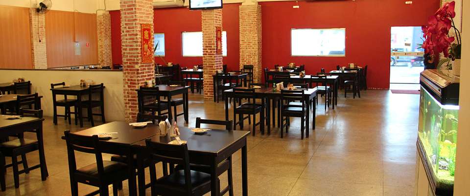 Salão do Sushi Itaquera com mesas pretas, paredes vermelhas e colunas de tijolo